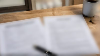 Homeowner reviewing an insurance claim document and roofing contract at a kitchen table