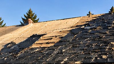Roof tear-off in progress on a Monticello home showing exposed decking before metal installation